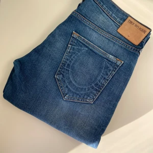 True Religion Jeans - Säljer ett par äkta True Religion jeans i storlek W32. Klassisk modell med snygga detaljer och ikoniska sömmar. Bra skick utan större slitningar eller fläckar. Perfekta för dig som vill ha en stilren men edgy look. Nypris ca 2000–2500 kr.