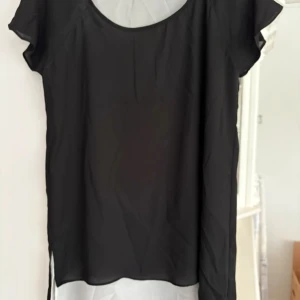 Svart blus från Punto Roma - En stilren svart blus från Punto Roma med rund halsringning och korta ärmar. Tillverkad i ett lätt och mjukt material som ger en snygg och enkel look. Perfekt att matcha med både jeans och kjol.