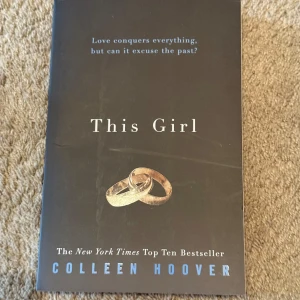 This Girl (oanvänd) - Säljer boken 'This Girl' av Colleen Hoover. Omslaget är svart med två guldringar på framsidan och blå text. Boken är en pocketutgåva och tillhör genren fiction. Perfekt för dig som gillar romantik och känslosamma berättelser.