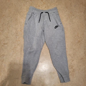 Grå nike tech byxor  - Säljer ett par grå nke tech byxor. Bra skick och är storlek 128-137 cm. Perfekt för vardagar och träningar. Snabb leverans. Pris 130kr. Om du har frågor, meddela mig.