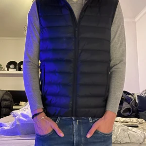 Svart dunväst från Dressmann - Säljer en svart dunväst från Dressmann med dragkedja framtill. Västen har en klassisk, vadderad design och passar perfekt över en tröja för extra värme. Enkel och stilren modell som är lätt att matcha till olika outfits. Säljer pga att jag är sugen på nått annat, köpt på dressman för 699kr🤩