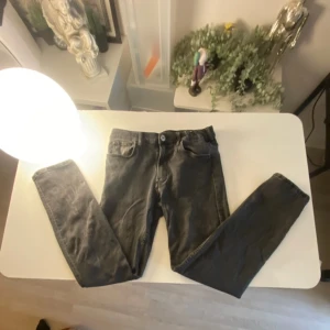 Svarta jeansbyxor från H&M - Säljer ett par svarta jeansbyxor från H&M med klassisk femficksdesign och raka ben. Byxorna har normal passform och är tillverkade i bomull med en liten mängd stretch för extra komfort. Perfekta till vardags och enkla att matcha.