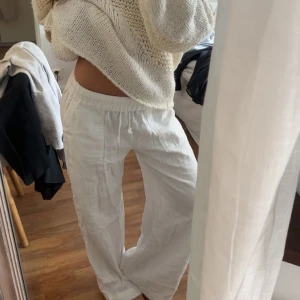 Vita linnebyxor  - Säljer ett par vita linnebyxor med avslappnad passform. Byxorna har raka, vida ben och resår i midjan för extra komfort. Perfekta för varma dagar och en chill stil.
