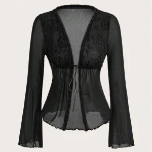 Svart spetsblus med knytning - Säljer en svart blus med långa ärmar och vacker spets upptill. Blusen har knytning framtill och är lätt transparent med volangkant nedtill. Perfekt för dig som gillar romantiska detaljer och en feminin look.