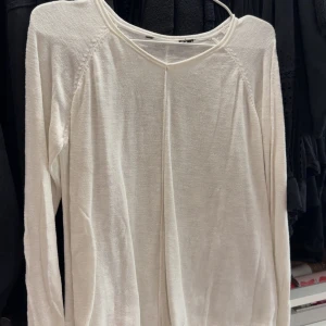 Vit långärmad tröja från H&M - En enkel och stilren vit långärmad tröja från H&M. Tröjan har en rund halsringning och är tillverkad i ett tunt, mjukt material som passar perfekt för lager-på-lager. Perfekt basplagg i garderoben.