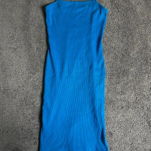 Blå ribbad långklänning - Säljer en blå ribbad långklänning med ärmlös design. Klänningen har en rak och enkel siluett, perfekt för varma dagar eller sommarens tillfällen. Materialet är stretchigt och följsamt.