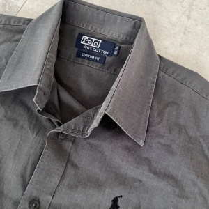 Grå skjorta från Polo Ralph Lauren - Snygg grå skjorta från Polo Ralph Lauren i 100% bomull. Extremt bra skick, passar vid festliga tillfällen samt chill dagar. Skick 9/10, storlek M, fraktar alltid samma dag eller dagen efter. (Pris kan diskuteras)