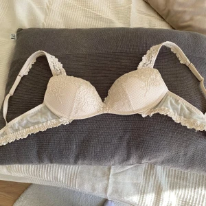 Beige spets-bh , Intimissimi super pushup 75 b - Säljer en cremefärgad bh från Intimissimi pretty flowers med super pushup och med  fina spetsdetaljer längs axelband och kanter. Bh:n har justerbara axelband och hakknäppning bak. Perfekt för dig som gillar romantiska och feminina underkläder. Den är sparsamt använd max 2-3 ggr!💞