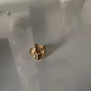 Guldfärgad ring med organisk form - Cool ring i guldfärg med en unik, organisk och lite abstrakt design. Perfekt för dig som vill sticka ut med dina accessoarer och gillar trendiga smycken med en twist.