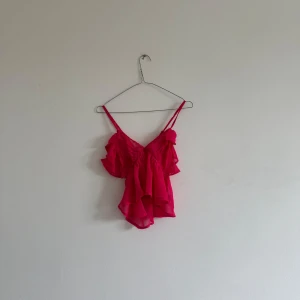 Rosa volangig linnetopp från ASOS  - Säljer en superfin rosa linnetopp från ASOS DESIGN med volangdetaljer och smala axelband. Toppen är luftig och har en croppad passform, perfekt till sommaren. Materialet är lätt och perfekt för sommaren! 