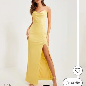 Splitterny gul balklänning💛 - Säljer en ljusgul långklänning i satin från Nelly. Klänningen har tunna axelband som korsas i ryggen och en snygg draperad urringning framtill. Perfekt för bal💛