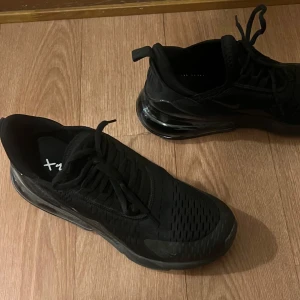 Svarta Nike Air Max 270 sneakers - Ett par skor jag fått i present, har två par sedan innan och behöver därför it de. Säljer ett par helsvarta Nike Air Max 270 sneakers med synlig luftbubbla i sulan och klassisk Nike-logga på sidan. Skorna har snörning och en sportig design som passar perfekt till streetwear och vardagsoutfits.