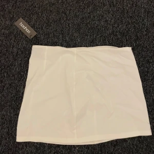 Vit mini kjol - Säljer denna Low rise mini kjolen från Boohoo. Kjolen är oandvänd 
