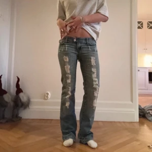 Seven7 ljusblå jeans med slitningar och pärldetaljer - Säljer ett par gulliga jeans i ljusblå denim med slitningar och pärldetaljer längs framsidan. Byxorna har låg midja, raka ben och klassisk femficksdesign. Perfekta för dig som vill ha en cool och unik look. (Lånade bilder💕).                                  Midjemått:37,5          Innebenslängd:79,5