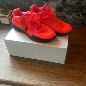 Nike by you Sabrina 2 - Säljer ett par Nike Sabrina 2 sneakers i en riktigt snygg neonrosa färg med svarta detaljer och svart sula. Skorna har snörning och är designade för basket men funkar även till vardags. Snyggt mönster på sidan och SABRINA-tryck på innersulan.