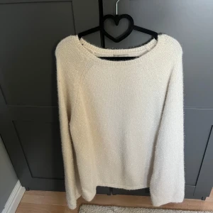 Vit stickad tröja med glittriga detaljer - Säljer en vit stickad tröja med diskret glittrigt garn. Tröjan har rund halsringning och långa ärmar. Perfekt för dig som vill ha en enkel men ändå lite extra tröja till garderoben.