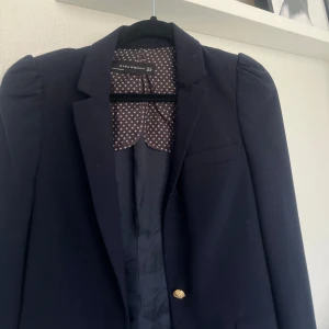 Figursydd kavaj från Zara - Mycket fin kavaj från Zara, marinblå med gulddetaljer. Figursydd med puffärm. Inga defekter, använd 1 gång. 