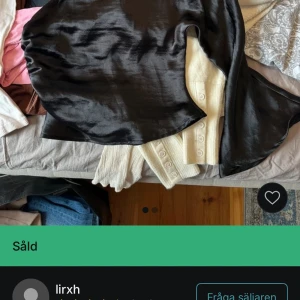 Svart oneshoulder topp i satin - Säljer en svart oneshoulder topp i glansigt satinmaterial. Toppen har en lång ärm och en axel är bar, vilket ger en cool och trendig look. Perfekt för dig som vill sticka ut lite extra.