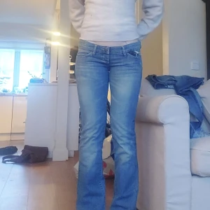Blå bootcut jeans med låg midja - Sjukt snygga lågmidjade bootcut jeans i nyskick!! Står inget märke men köpta secondhand Innerbenslängd: 80cm Midjemåttet tvärs över: 42 (går att reglera till mindre) OBS! Det finns ingen dragkedja, men det finns resor (bild). Har inte varit något problem att få på sig jeansen för mig Utan bara suttit bättre eftersom att man kan justera själv