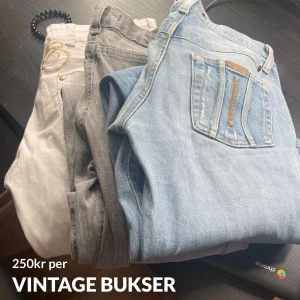 Vintage jeansbyxor i olika färger - Tre par vintage jeansbyxor i ljusblått, grått och vitt. Klassisk femficksmodell med detaljerade sömmar och broderi på det vita paret. Perfekta för dig som gillar retrostil och vill ha unika jeans i garderoben.