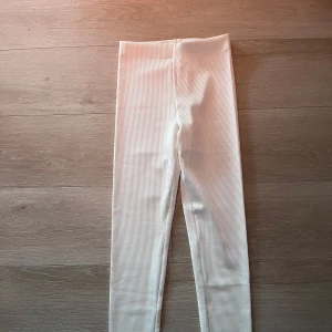 Vita ribbade leggings - Säljer ett par vita leggings med ribbad struktur. De är tighta och har hög midja, perfekta för en stilren och enkel look. Passar bra till både oversized tröjor och crop tops.