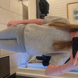 Ljusgrå stickad tröja från Gina Tricot - Mysig ljusgrå stickad tröja från Gina Tricot med korta ärmar och rund halsringning. Tröjan har en fluffig känsla och är perfekt för lager-på-lager-stil. Enkel och stilren design som passar till det mesta.