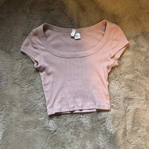 Rosa ribbad tröja - Jag säljer en rosa ribbad magtröja från HM. Med en djup u-ringad hals.