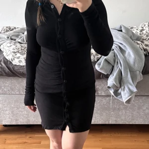 Svart långärmad klänning  - Säljer en svart, tight långärmad klänning med knappar hela vägen framtill som går att justera. Klänningen är kort och har en figurnära passform🤍