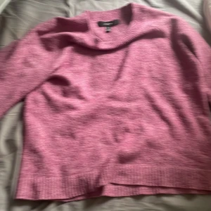 Rosa stickad tröja från Vero Moda - Mysig rosa stickad tröja från Vero Moda. Tröjan har en klassisk rund halsringning och långa ärmar. Perfekt för lager-på-lager och passar till både jeans och kjol. Enkel och stilren design som är lätt att matcha.
