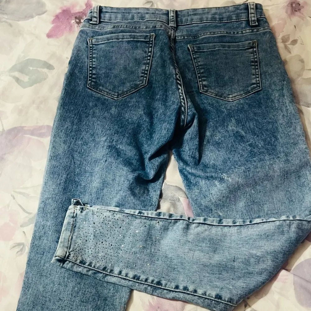 Snygga blå jeans från Kapalua med klassisk femficksdesign och skinny fit. Jeansen har hög midja och är dekorerade med små strassdetaljer på framsidan av benen för en extra touch. Perfekta att styla till olika outfits.. Farkut & Housut.