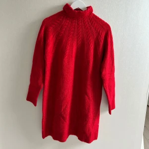 Röd stickad långklänning med polokrage - Säljer en röd stickad långklänning med polokrage och kabelstickat mönster upptill. Klänningen har långa ärmar och ribbade muddar. Den är super mysig när det är lite kallare eller perfekt till julen💗💗