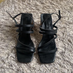 Svarta klackar - Säljer ett par svarta klackar. Skorna har en stabil blockklack och justerbar rem runt vristen. Perfekta för dig som gillar stilrena och trendiga skor. Använda fåtal gånger, gått sönder vid klacken underifrån som syns på sista bilden, men det syns inte när man har dom på💖