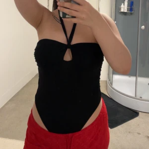 Svart body från NA-KD - Säljer en svart body från NA-KD med halterneck och knyt i nacken. Bodyn har en liten öppning framtill. Aldrig kommit till användning!