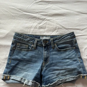 Blå jeansshorts med fransig kant - Säljer ett par blåa jeansshorts. Shortsen har fem fickor och fransig kant nertill. Perfekta för sommaren. 