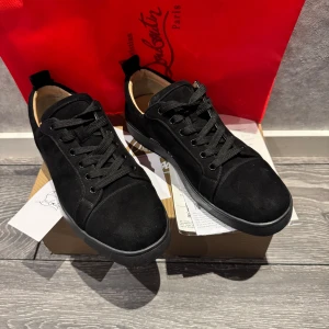 Svarta Christian Louboutin - Säljer ett par svarta sneakers från Christian Louboutin med klassisk röd sula. Skorna har snörning och är tillverkade i mocka med svarta detaljer. Perfekta för dig som vill ha en stilren och lyxig look. Dem är rena, kommer att cleana dem innan dem skickas också. Priset gör att diskutera 
