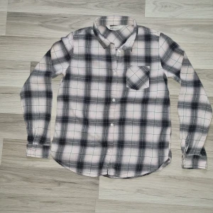 Rutig skjorta från H&M i svart och ljusrosa - Säljer en rutig skjorta från H&M i svart och ljusrosa toner. Skjortan har lång ärm, klassisk krage, bröstficka och knäppning framtill. Perfekt för en avslappnad och stilren look.