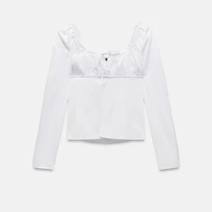 Vit långärmad blus med knyt från Zara - Säljer en vit långärmad blus från Zara med söt knytning framtill och rynkade detaljer vid halsringningen. Blusen har en feminin och stilren design, perfekt att matcha med jeans eller kjol.