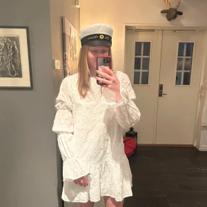 Vit klänning med spetsdetaljer, studentklänning  - Jättefin Studentklänning! en söt vit klänning med spetsdetaljer och volanger. Klänningen har långa ärmar och en öppen rygg som ger en elegant touch. Perfekt för sommarens festligheter! 🌸knytning i ryggen! Aldrig använd, prislapp sitter kvar! Köpt för 699