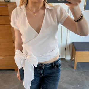 Vit blus med rosett  - Superfin blus med påsydd långa band som kan knyta till en snygg rosett fram eller bak! Liten i storleken så sitter mer som en XS-S!❣️🥰