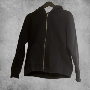 Svart hoodie med dragkedja från Zara - Säljer en stilren svart hoodie från Zara med dragkedja framtill. Perfekt för en avslappnad look. Den har en klassisk huva och långa ärmar.