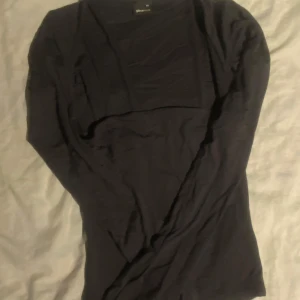  Långärmad topp från Gina Tricot - Säljer en stilren svart långärmad topp från Gina Tricot. Enkel och mångsidig design som passar till det mesta. Har aldrig använt den. Kvaliten är superbra, toppen har jätte skönt material. Priset kan diskuteras. Toppen är inte riktigt svart, den är mer mörk grå färg.