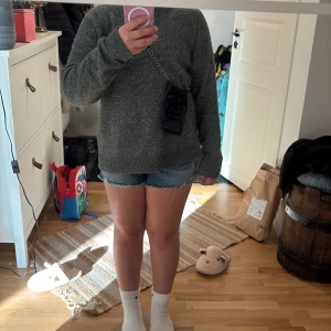 Svart axelväska med rosdetalj till iPhone 7 - Snygg svart axelväska i skinn med en stor rosdetalj på framsidan. Väskan har en kedja som axelrem och är perfekt för att bära med sig det viktigaste. En stilren accessoar som passar till många olika outfits.