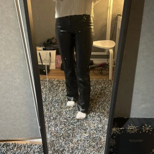 Svarta skinnbyxor - Snygga svarta skinnbyxor med en tight passform och utsvängda ben. Byxorna har en hög midja och en stilren design som passar perfekt för en trendig look. 