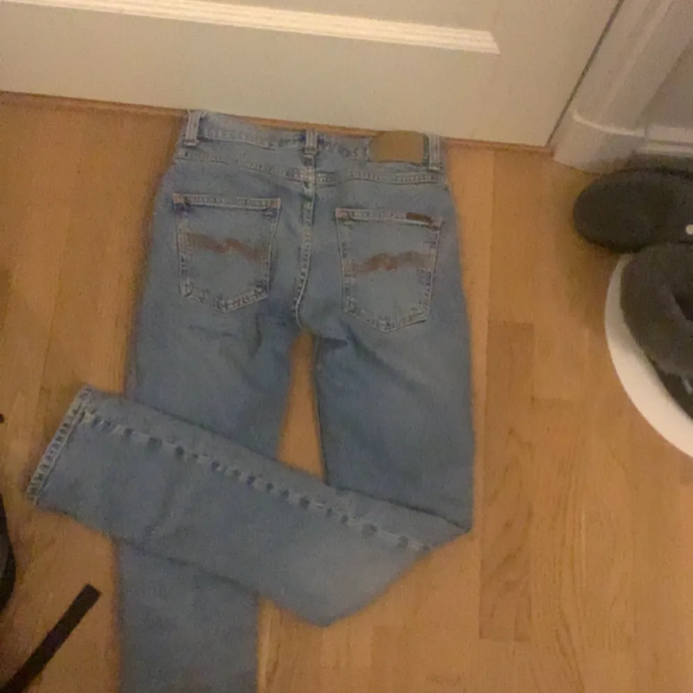 Säljer ett par klassiska blå jeans från Nudie Jeans. De har en normal passform och är tillverkade i denim. Jeansen har en traditionell femficksdesign och en knappgylf. Perfekta för en avslappnad stil.. Farkut & Housut.