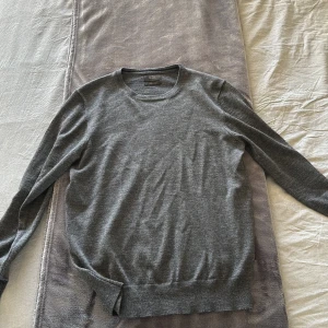 Grå tröja från Nordic Design Lab - Säljer en stilren grå tröja från Nordic Design Lab i mjuk merinoull. Tröjan har en klassisk rund hals och långa ärmar, perfekt för kyligare dagar. Den är enkel och elegant, vilket gör den lätt att matcha med olika outfits.