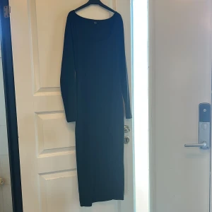 Svart ribbad långklänning - Snygg svart långklänning med ribbad struktur och långa ärmar. Perfekt för en stilren look. Klänningen har en enkel design som gör den lätt att matcha med olika accessoarer.