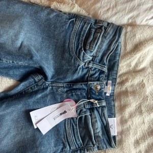Blå jeansbyxor  - Snygga blå jeansbyxor från Gina med klassisk femficksdesign och knappgylf. Perfekta för en avslappnad stil. De har en rak passform och är tillverkade i slitstarkt denim. Stl 158 tall, aldrig använda
