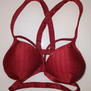 Röd bikini - Snygg röd danstopp/sportbh/bikiniöverdel från Lurefitness. Mångfaldig användning, köptes till dans under en bolero men har inte kommit till användning. Den har en unik design med flera band som korsar ryggen.