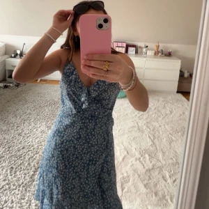 Blå blommig klänning - Så vacker blå omlottklänning perfekt till sommaren och nu till våren! Med knyte på ryggen som bildar en rosett🎀🤍 Aldrig använd endast testad, står att storleken är L men den passar mig som har Xs/S🤍KOLLA GÄRNA IN ANNAT JAG SÄLJER DÅ JAG SKA TILL USA OCH VILL FÅ SÅLT ALLT