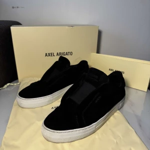 Svarta sneakers axel arigato - Hej säljer nu mina supersnygga arigatos i mocka. Skorna är i bra skick o passar perfekt till sommaren.  Box och dustbags medföljer. Vid frågor eller funderingar är det bara att skriva🙏❤️